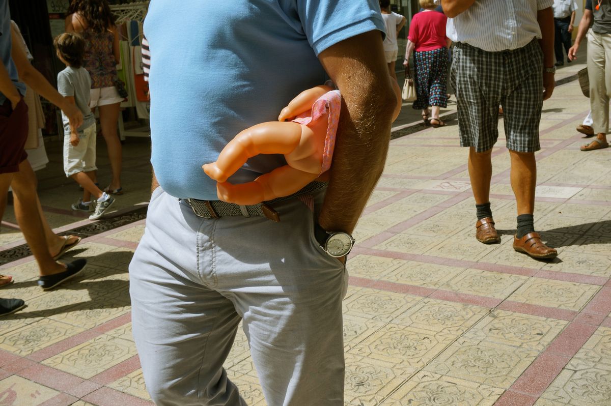 Man with a doll walking down a street in Vila Real de Santo António (South Portugal)